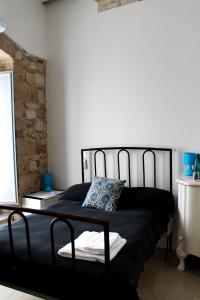 - un lit noir dans une chambre avec un mur en pierre dans l'établissement Il Mulino di Amleto - Bed and Breakfast letterario, à Molfetta