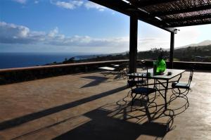 una mesa y sillas en un patio con vistas al océano en Horizon Pantelleria, en Pantelleria