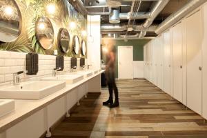 a man standing in a bathroom with sinks and mirrors at Urban Camper Hostel & Bar in Copenhagen +24 photos