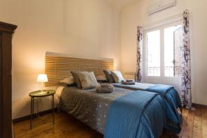 una camera da letto con un letto con una coperta blu e una finestra di Terrazza Politeama a Palermo