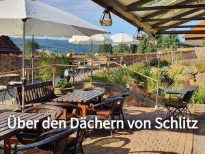 a patio with a table and chairs and umbrellas at Hotel & Café Schachtenburg in Schlitz