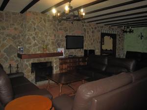 Una sala de estar con muebles de cuero y chimenea. en casa rio alberche y el cortijo de gredos, en Navaluenga