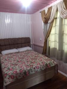 Un dormitorio con una cama con una manta de flores y una ventana en Casa de temporada da vovó, en Urubici