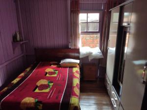 a small bedroom with a bed with a red blanket at Casa de temporada da vovó in Urubici