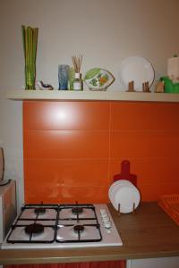 a stove top in a kitchen with an orange wall at i 2 puttini in Catania