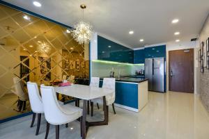 Il comprend une cuisine et une salle à manger avec une table et des chaises blanches. dans l'établissement Căn hộ Quận 4 GoldView Aparment, à Hô-Chi-Minh-Ville