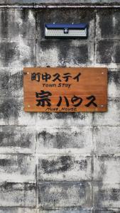 a sign on a brick wall with asian writing on it at 町中ステイ 宗ハウス in Nachikatsuura