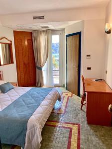 a bedroom with a bed and a desk and a window at Hotel Della Baia in Portovenere