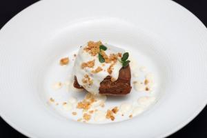 a white plate with a piece of cake with white frosting at Hotel Du Soleil in Rimini