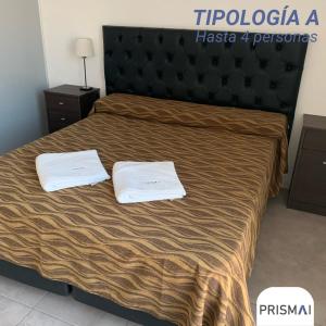 a hotel room with a bed with two towels on it at Edificio PRISMA I in Villa Carlos Paz