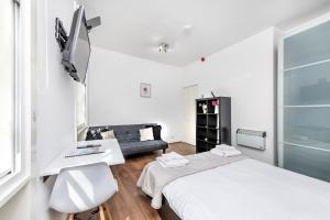 um quarto branco com uma cama e um sofá em Soho Central Apartments em Londres