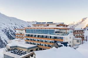 a hotel in the snow with mountains in the background at SKI - GOLF - WELLNESS Hotel Riml in Hochgurgl