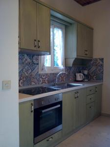 cocina con armarios de madera, fregadero y ventana en Lena Blue Sea Apartments en Kalami