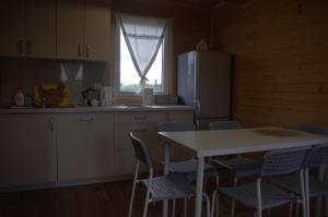 a kitchen with a table and chairs and a refrigerator at Cisowe Domki Nowęcin in Nowecin