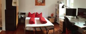 Schlafzimmer mit einem Bett mit roten Kissen und einem Schreibtisch in der Unterkunft B&B Tomsi in Pratteln