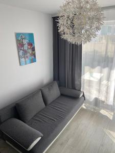 un sofá en una sala de estar con una lámpara de araña en Apartamenty Bursztynowe w Kołobrzegu Sun&Relax, en Kołobrzeg