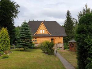 une maison en bois avec un toit noir dans une cour dans l'établissement Dworek nad Potokiem, à Karpacz