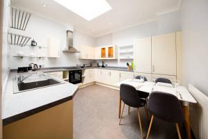 a kitchen with white cabinets and a table and chairs at Clifton Spacious 3 Bed Apt & Parking - Simplycheckin in Bristol