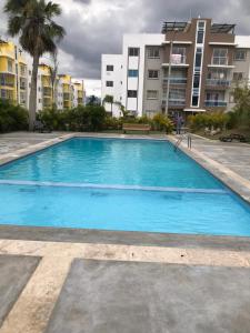 uma grande piscina azul com edifícios ao fundo em moderno apto frente a la piscina em Santiago de los Caballeros