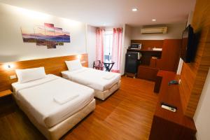 a hotel room with two beds and a television at Thaiphiphat house in Bangkok