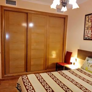 a bedroom with a large wooden cabinet next to a bed at Apartamento a 50 metros de la playa Muchavista in El Campello +36 photos