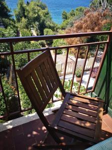una silla de madera sentada en un balcón con vistas al océano en Apartments Sara Maris, en Prizba