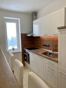 a kitchen with white cabinets and a sink and a window at Apartmán Linda in Abertamy