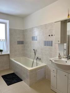 ein Badezimmer mit einer Badewanne und einem Waschbecken in der Unterkunft Apartmán Linda in Abertamy
