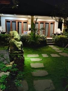 a garden with a statue in front of a house at Putu's Paradise Guesthouse in Ubud