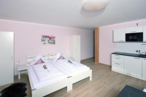 a bedroom with a white bed and white walls at Pension Lerchenfeld in Schongau