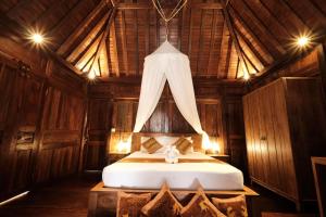 1 dormitorio con 1 cama en una habitación de madera en Bumbung Sari Villa, en Ubud