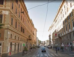 Une voiture qui descend dans une rue urbaine avec des bâtiments dans l'établissement Heart of Rome Vatican Deluxe New Apartment 1GB WiFi, à Rome