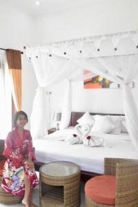 a young girl sitting in front of a bed at The Barari Villas in Pemuteran