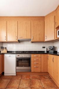 a kitchen with wooden cabinets and a white dishwasher at Apartamentos El Llombo in Ontinyent