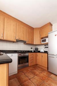 cocina con armarios de madera y nevera blanca en Apartamentos El Llombo, en Ontinyent
