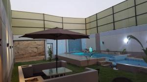 a patio with an umbrella and a swimming pool at شاليهات العرسان بمسبح وبدون مسبح بمحايل عسير ترقش in Turghush