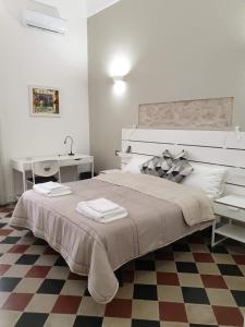 - une chambre blanche avec un grand lit et un bureau dans l'établissement Duomo Rooms b&b, à Lentini