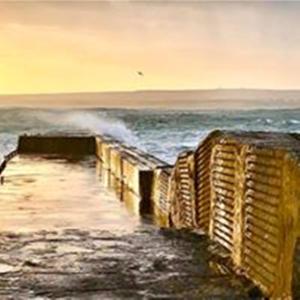 a view of the ocean with waves crashing on a pier at Windhaven Camping and B&B in Thurso