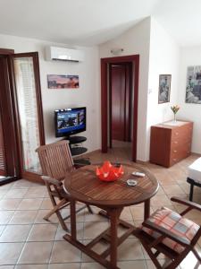 Da Claudio gli oleandri residence في أولبيا: غرفة معيشة مع طاولة وكراسي وتلفزيون