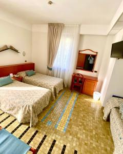 a hotel room with two beds and a tv at Hotel Della Baia in Portovenere