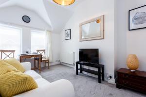 een woonkamer met een witte bank en een televisie bij Charming, Well-Equipped Apt - 5 Minutes From Beach in Bournemouth