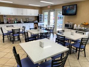 a restaurant with tables and chairs and a kitchen at Baymont by Wyndham Eden in Eden