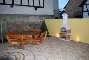 a patio with a table and benches and a pizza oven at Maison A Colombage De 1602 in Wintzenheim