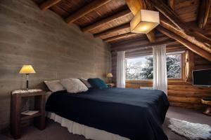 um quarto com uma cama grande num chalé de madeira em Hosteria Sudbruck em San Carlos de Bariloche