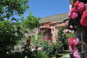 un jardín con rosas frente a un edificio en La Casa del tío Americano en Albarracín