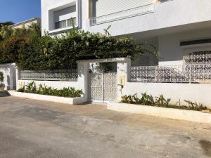 un bâtiment blanc avec un portail et une clôture dans l'établissement New cosy 2 bedrooms in La Marsa, à La Marsa