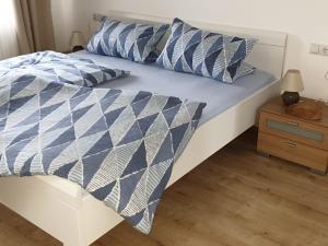 Bett mit blauer und weißer Bettdecke und Kissen in der Unterkunft Bodensee Ferienwohnung Claudia 4 in Friedrichshafen