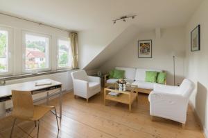 a living room with a white couch and chairs at Villa Brodthage, App. 1 in Walkenried