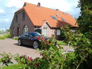 ein schwarzes Auto, das vor einem Haus parkt in der Unterkunft Huus Westerdiek in Neßmersiel