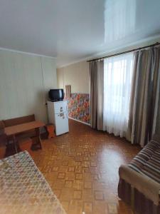 a living room with a bed and a tv at Arbuz Guest House in Zaliznyy Port